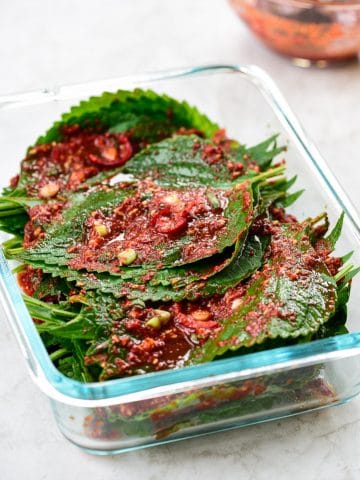 Red spicy perilla leaf kimchi in a pyrex container
