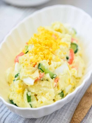 Mayo-based Korean-style potato salad dotted with boiled egg, cucumber, and carrot slices garnished with egg yolk powder