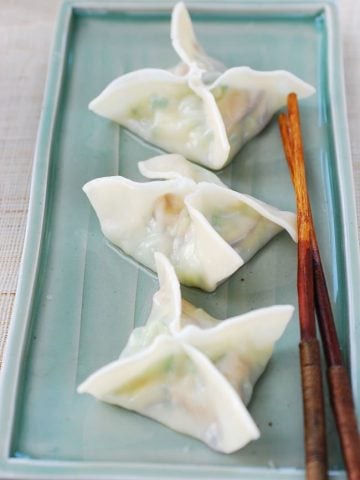 Three boiled zucchini dumplings in square or star shape on a green rectangle shape plate
