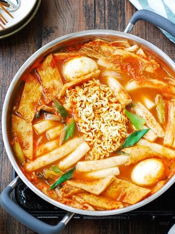 Korean spicy rice cakes with fish cake, boiled eggs and ramen noodles in the middle in a shallow pot