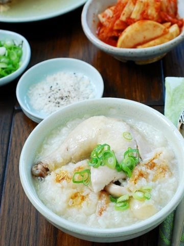 Chicken leg on top of rice porridge served with kimchi