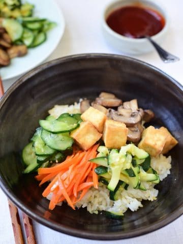 Tofu bibimbap in a large bowl with gochujang sauce
