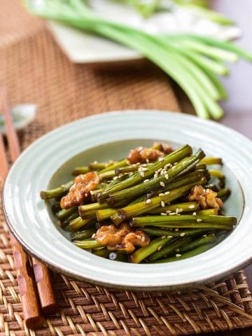 Garlic scapes stir-fried with walnuts and served in a small bowl as a side dish