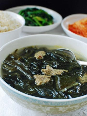 Miyeok guk (seaweed soup) with beef served with a bowl of rice, kimchi and spinach side